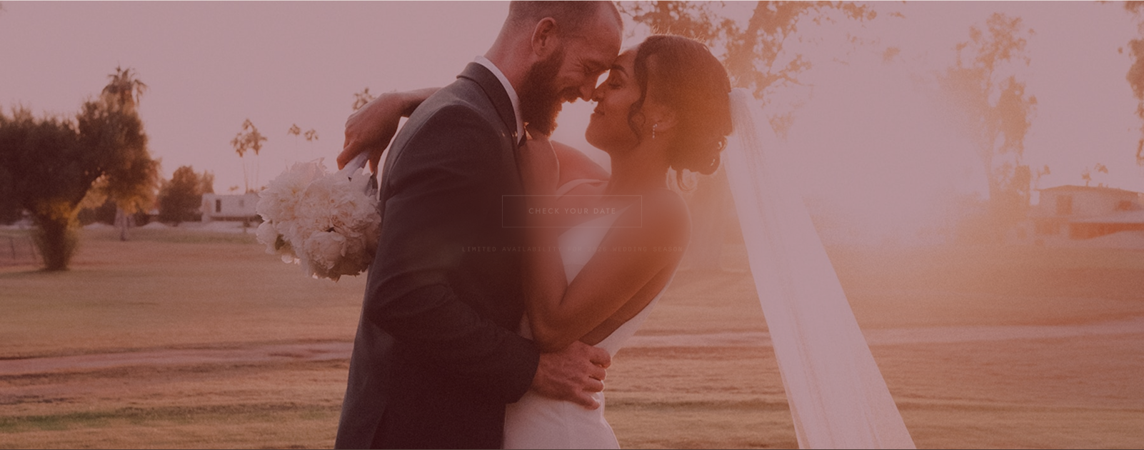 A couple leaning into each other at sunset, the bride's veil catching the last light